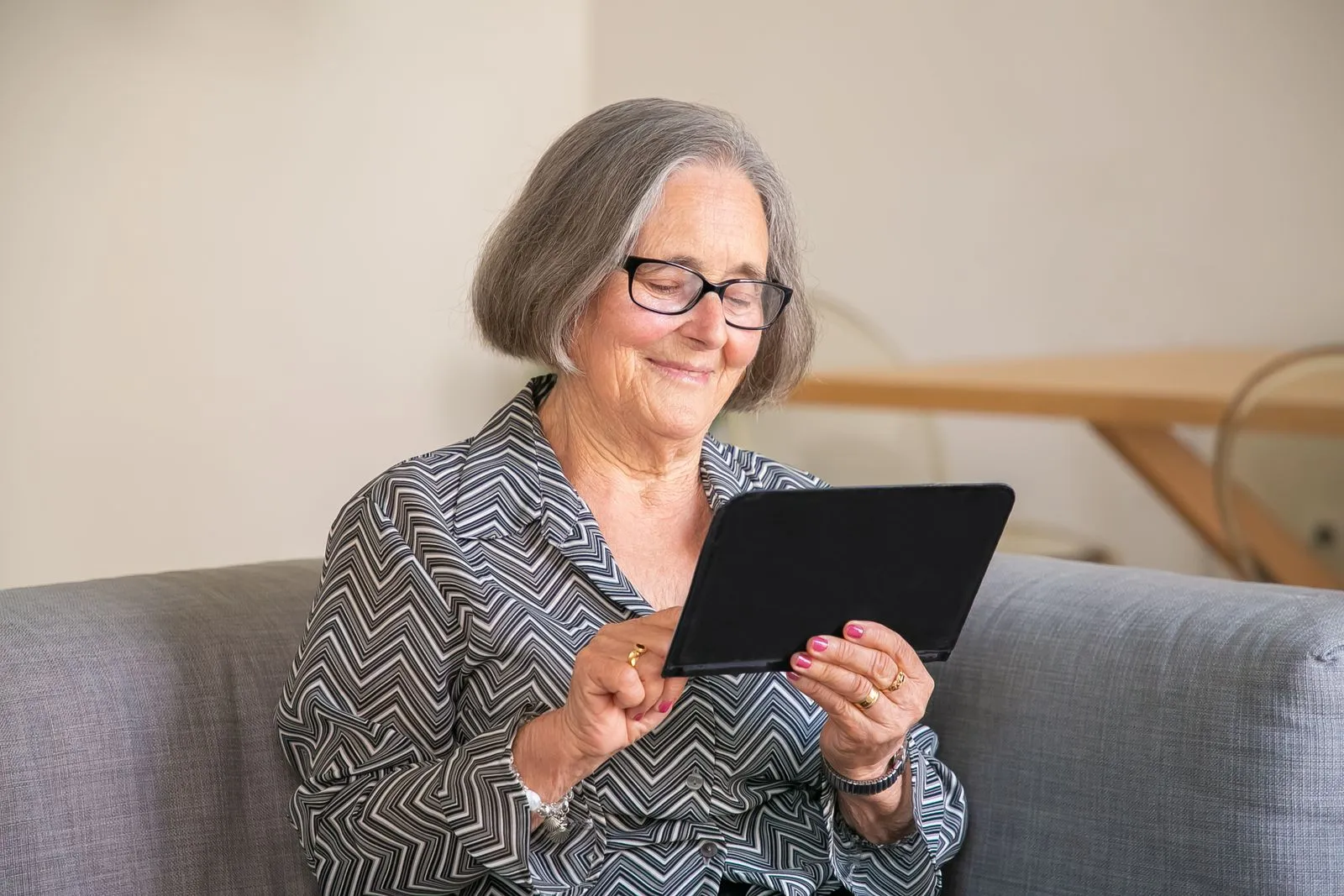 Personne senior découvrant le numérique avec le sourire, sur une tablette